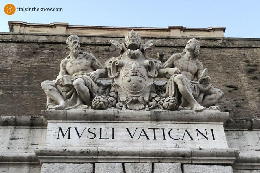 Vatican Museums entrance detail with statues of Michelangelo, Raphael, and the coat of arms of Pius XI