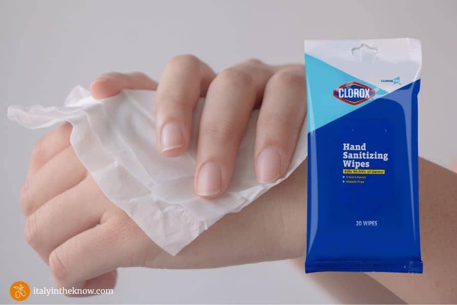 Two hands with a hand wipe overlaid with a package of hand sanitizing wipes