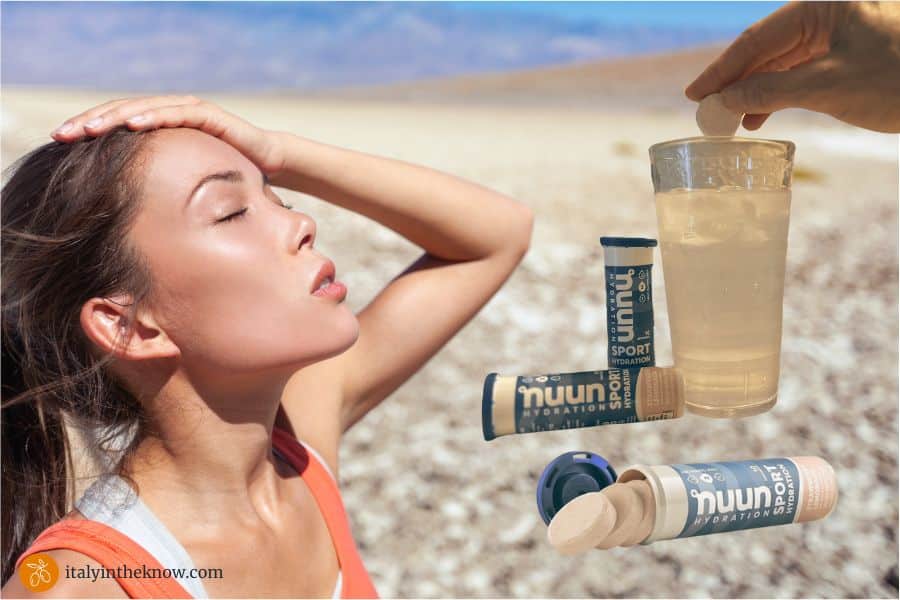 Woman who is overheated looking up at sun with glass of water and hydrating tablets