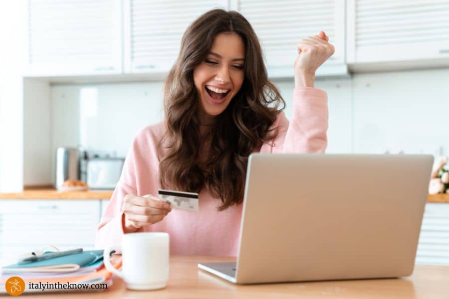 happy woman holding credit card and looking at laptop screen