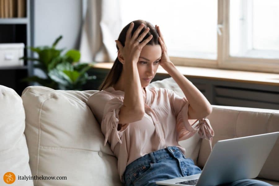 woman with hands on her head looking at a laptop screen