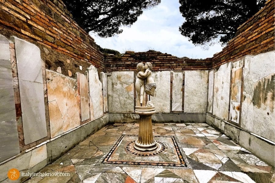 Room with patterned marble walls and floor and a statue of Cupid and Psyche in the center