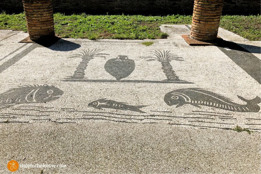 Floor mosaic showing three fish, an amphora, and two date palms