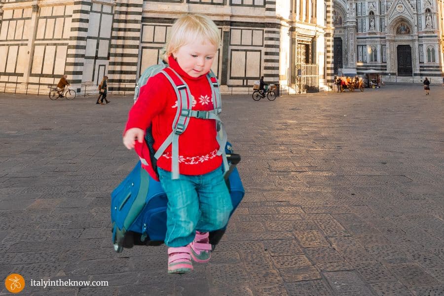 Child with backpack and suitcase in a piazza at the Florence Duomo Complex