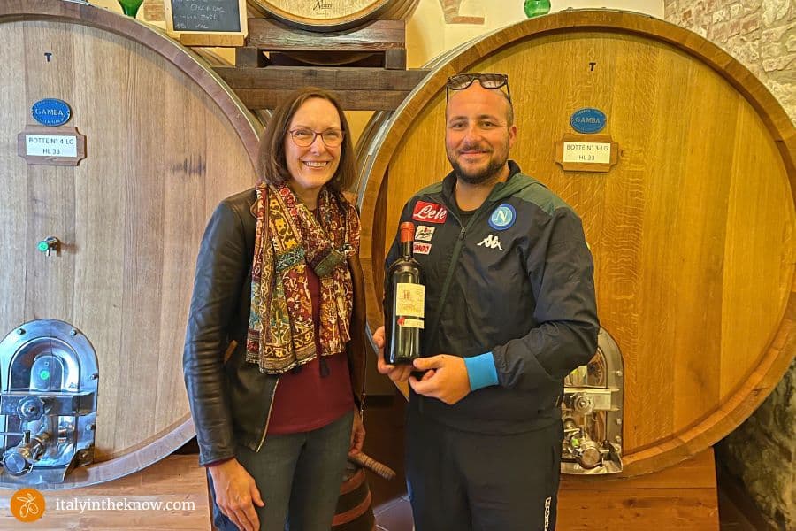 Angelo and Joyce with wine bottle and wine barrels