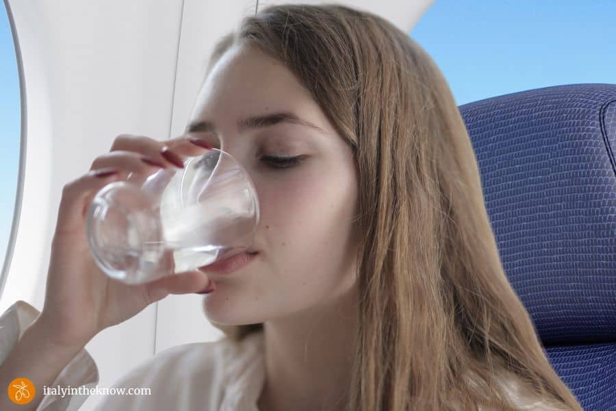 Woman drinking a glass of water in an airplane on a long flight.