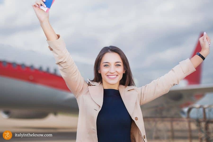 Woman with arms in the air in front of a jet.