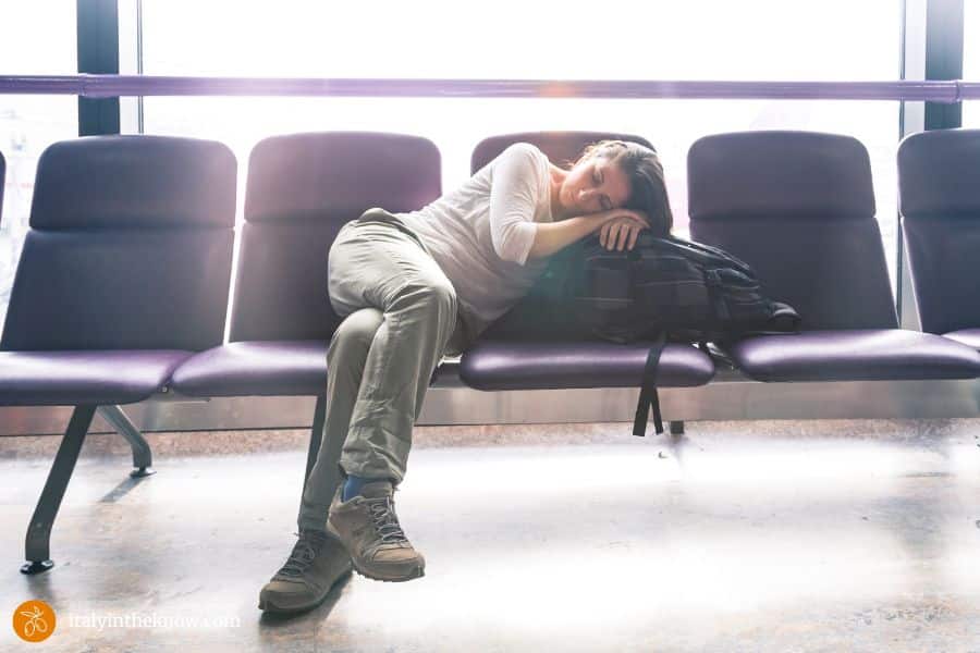 Exhausted woman in an airport taking a nap in a waiting area.